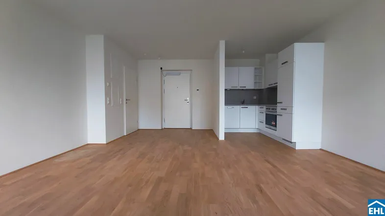 Heller offener Wohnbereich mit integrierter Küche und modernem Holzfußboden.