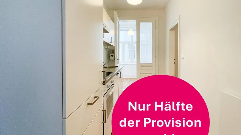 Helle Küche mit weißen Einbauschränken und Holzboden, die in einen Flur übergeht.
