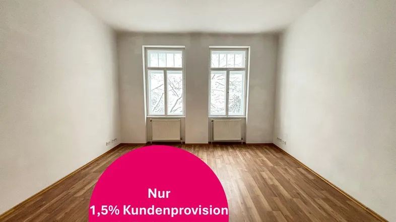 Heller, leerer Raum mit Holzboden, zwei Fenstern und Heizkörpern.