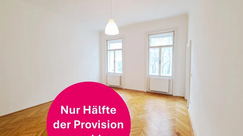 Heller, leerer Raum mit klassischem Fischgrätparkett, weißen Wänden und zwei großen Fenstern.