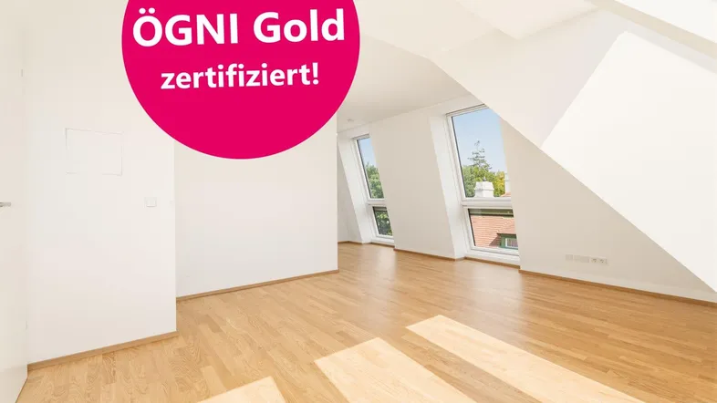 Heller Raum im Dachgeschoss mit Holzboden, schrägen Wänden und großen Fenstern, ÖGNI Gold zertifiziert.