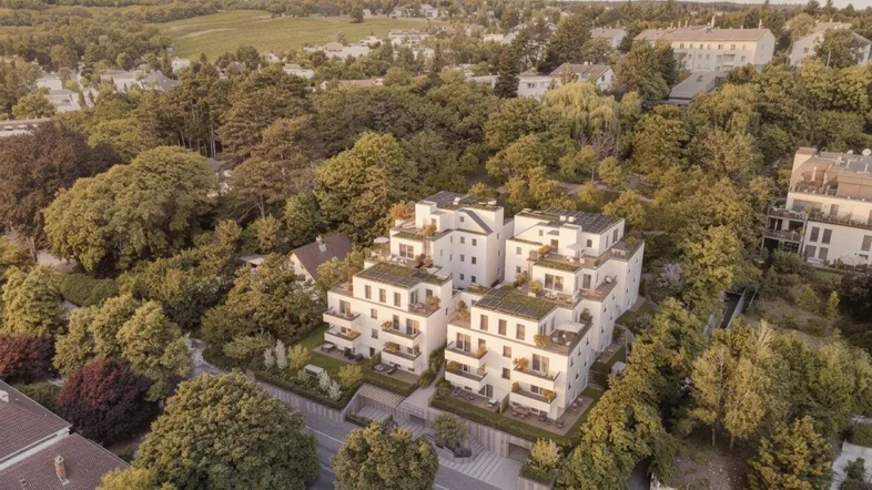 Moderne Wohnanlage mit mehreren Gebäuden, umgeben von viel Grün und mit Blick auf die Landschaft.