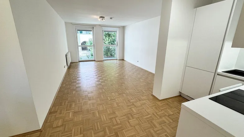Heller offener Wohnbereich mit Parkettboden und Zugang zu zwei französischen Balkonen.