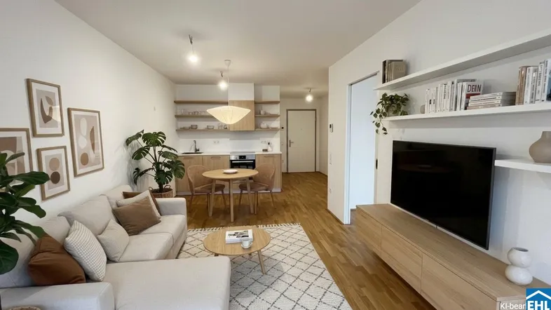 Helles, offenes Wohnzimmer mit integrierter Küchenzeile, Holzboden und modernem Mobiliar.