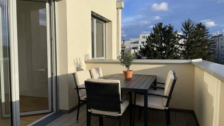 Heller Balkon mit Holzdielenboden und modernen Gartenmöbeln, bietet einen angenehmen Blick auf die Stadt.