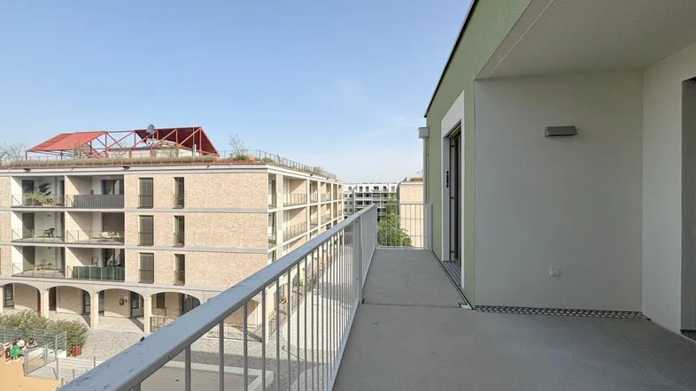 Geräumiger Balkon mit Blick auf moderne Wohngebäude und den blauen Himmel.