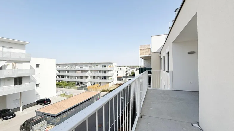 Geräumiger Balkon mit Blick auf die umliegenden modernen Gebäude und den Parkplatz.