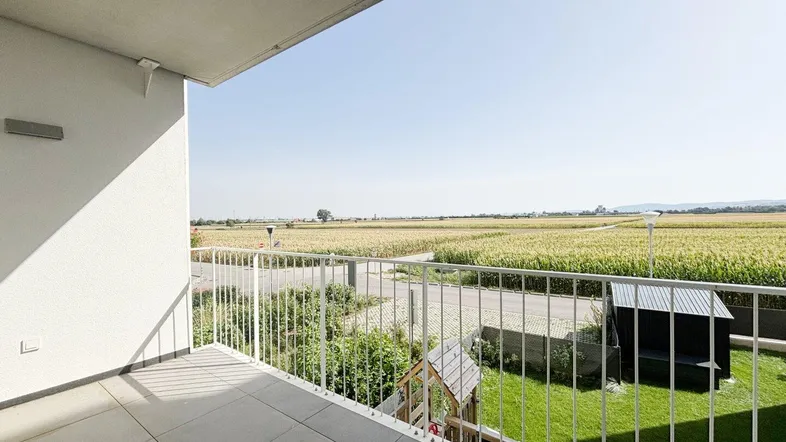 Balkon mit Fliesenboden und weitem Blick über Felder und die grüne Landschaft.
