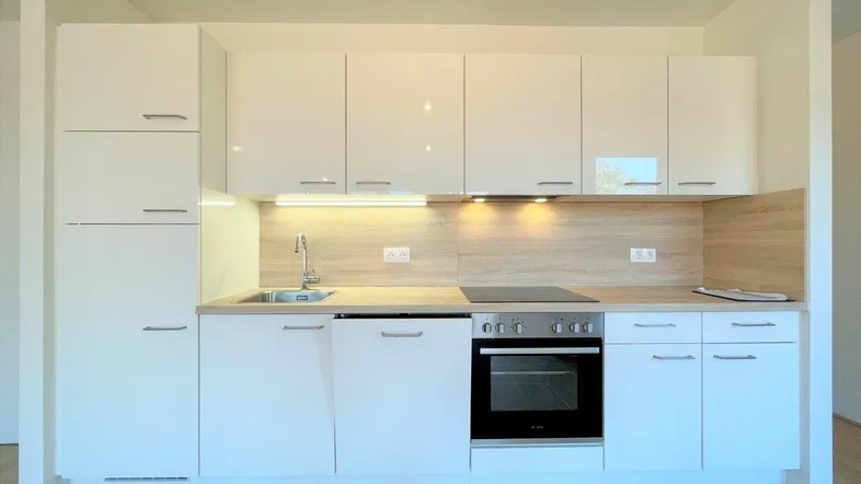 Moderne Einbauküche mit weißen Hochglanzfronten, Kochfeld und Backofen in neuwertigem Zustand.