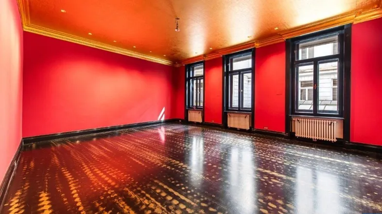 Geräumiger Raum mit leuchtend roten Wänden, goldener Decke und dunklem Fischgrätparkett.