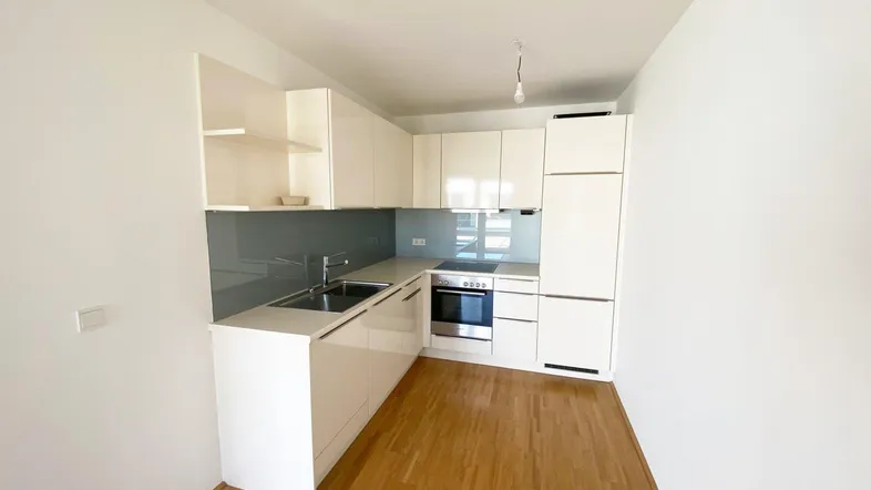 Moderne Einbauküche mit weißen Hochglanzfronten, integrierten Geräten und hellem Holzfußboden.