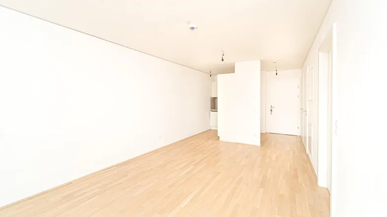 Helles, leeres Zimmer mit Parkettboden und weiß gestrichenen Wänden, bereit zum Einzug.