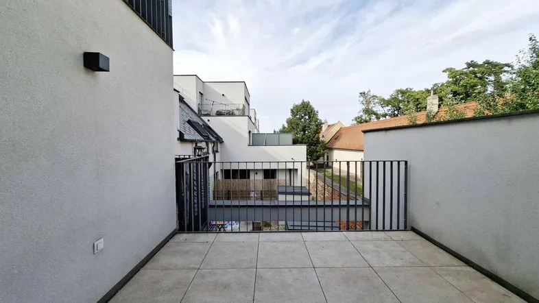 Moderne, geflieste Terrasse mit Blick auf die umliegenden Gebäude und den Himmel.