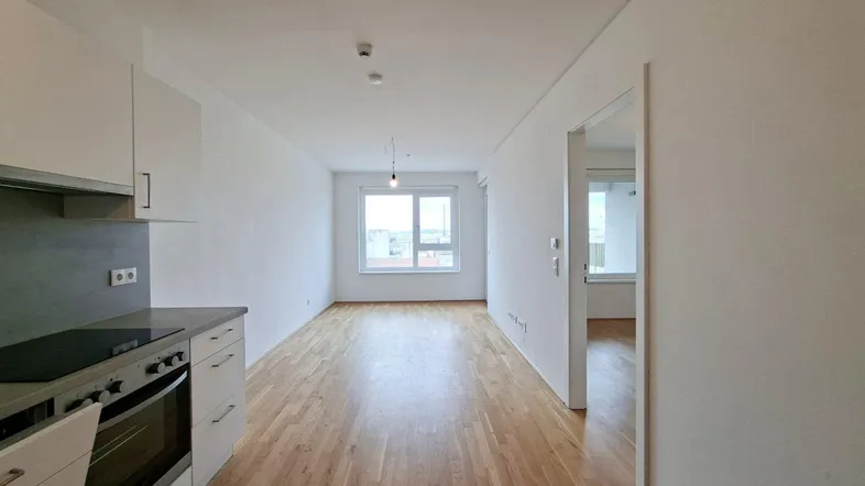 Helles, leeres Wohnzimmer mit Parkettboden und großen Fenstern, bereit zur individuellen Gestaltung.