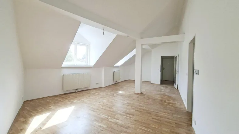 Helles Dachgeschosszimmer mit Holzboden und schrägen Wänden, bietet vielseitige Nutzungsmöglichkeiten.