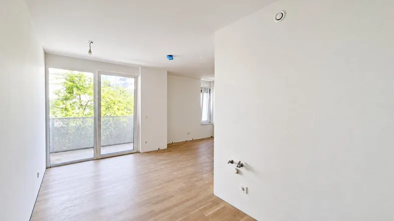 Helles Wohnzimmer mit neuem Holzboden und großem Balkonzugang, bereit zur individuellen Gestaltung.
