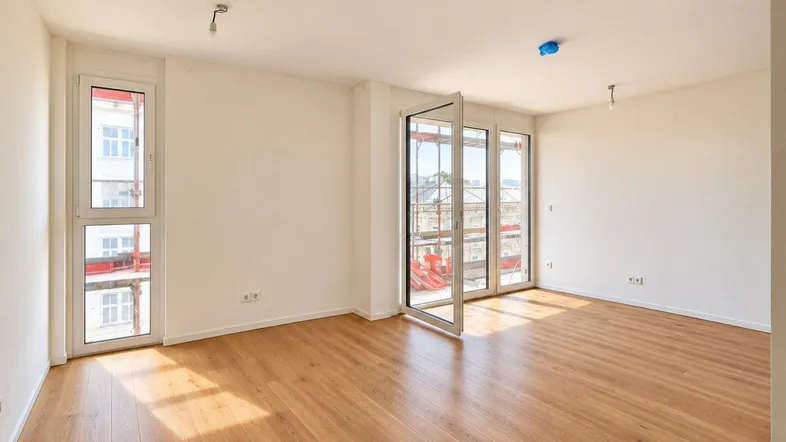 Heller, leerer Raum mit Laminatboden und Zugang zu einem französischen Balkon, ideal als Wohnzimmer.