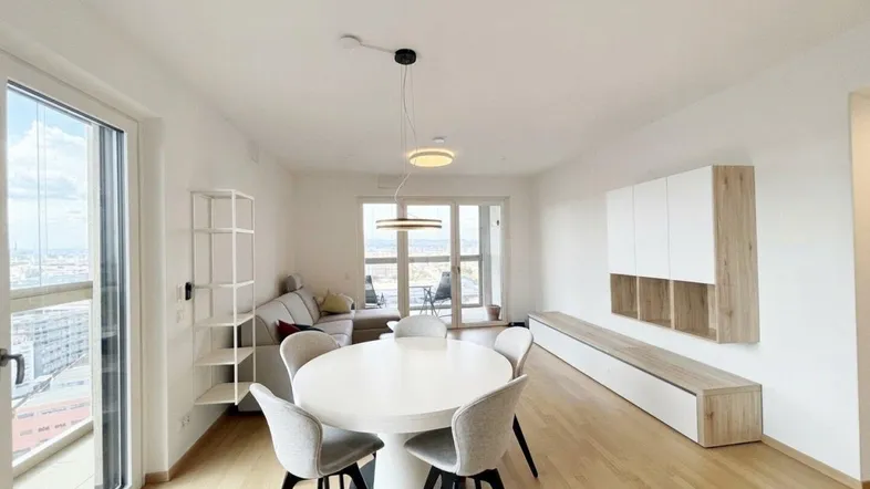 Heller Wohn- und Essbereich mit modernem Design, Holzboden und Zugang zum Balkon mit Stadtblick.