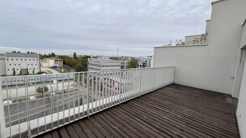 Geräumige Terrasse mit Holzboden und weißem Geländer, bietet einen weiten Blick über die Stadt.
