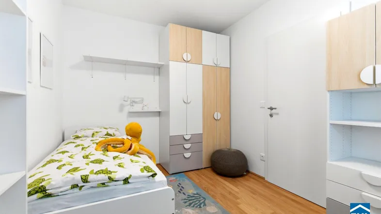 Helles Kinderzimmer mit Einzelbett, Holzschrank und Parkettboden, ideal für junge Bewohner.