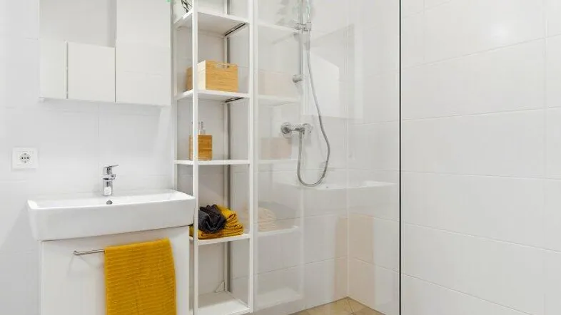 Modernes Badezimmer mit ebenerdiger Dusche, Waschbecken und hellen Fliesen.