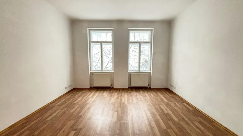 Heller, leerer Raum mit hohen Decken, zwei Fenstern und schönem Holzboden, ideal für individuelle Gestaltung.