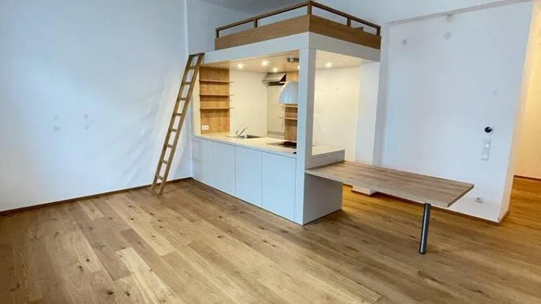 Heller Wohnraum mit Holzboden, integrierter Küchenzeile und Hochbettlösung.