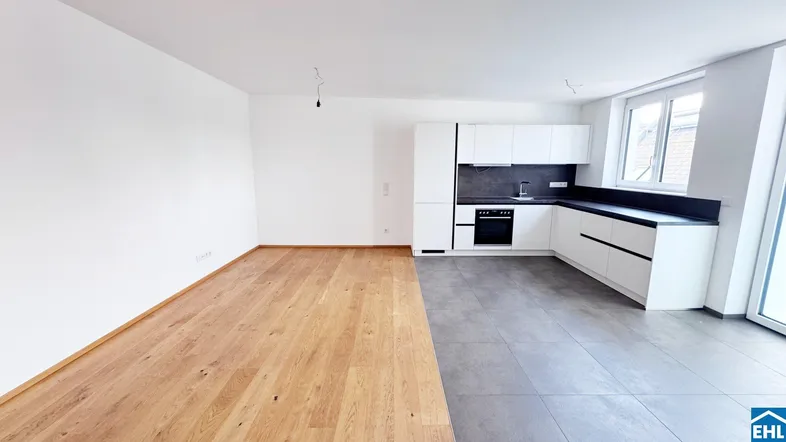 Heller offener Wohnbereich mit moderner Einbauküche, Holzboden und Fliesen in neuwertigem Zustand.