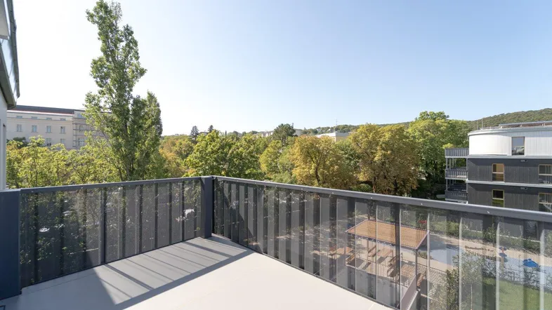 Geräumiger Balkon mit moderner Metallbrüstung und weitem Blick ins Grüne.
