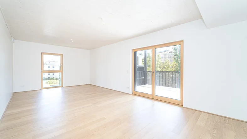 Helles, leeres Wohnzimmer mit Holzboden und Zugang zu einem Balkon, ideal für individuelle Gestaltung.