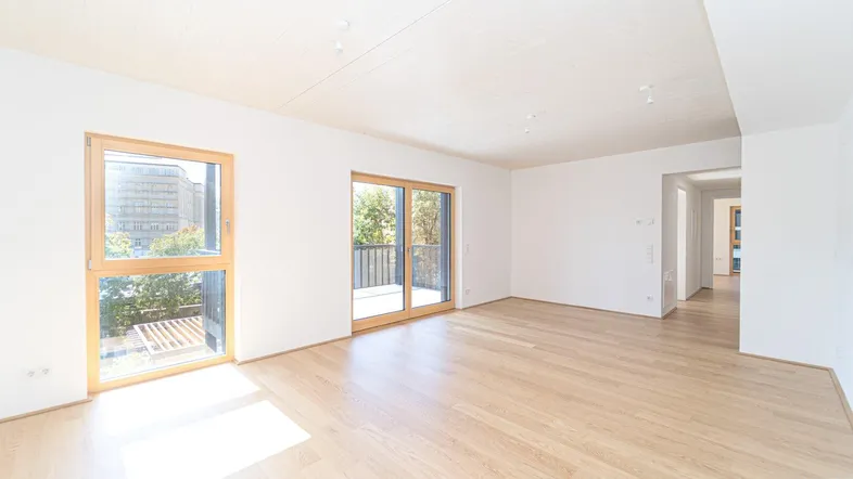 Helles, leeres Wohnzimmer mit Holzboden und Zugang zu einem Balkon, bereit zur individuellen Gestaltung.