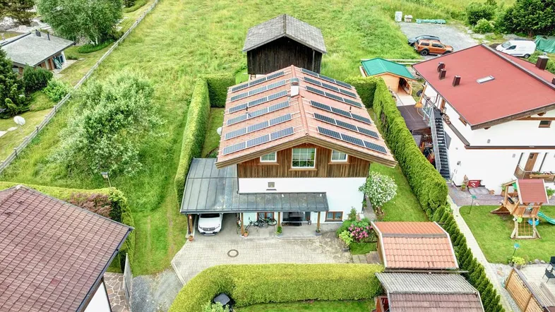 Luftaufnahme eines Hauses mit Solaranlage, umgeben von grünen Hecken und Rasenflächen in ländlicher Umgebung.