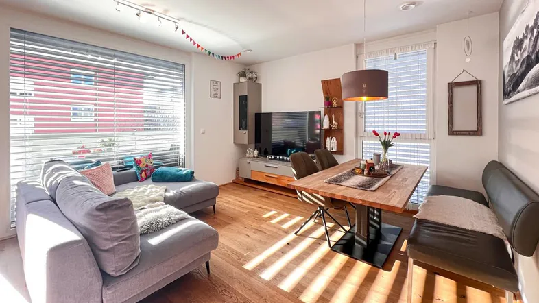 Helles Wohn- und Esszimmer mit Holzboden, bequemer Couch und Esstisch für gesellige Stunden.