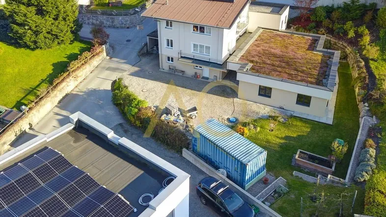 Luftaufnahme des Anwesens mit Photovoltaikanlage auf dem Dach und umliegender Grünfläche.