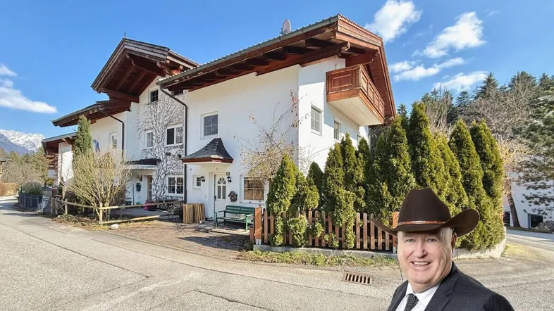 Traditionelles Haus mit weißer Fassade, Holzelementen und umgebender Natur.