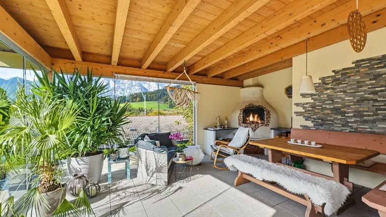 Gemütlicher Wintergarten mit Holzbalkendecke, Kamin und Bergblick, ideal zum Entspannen.
