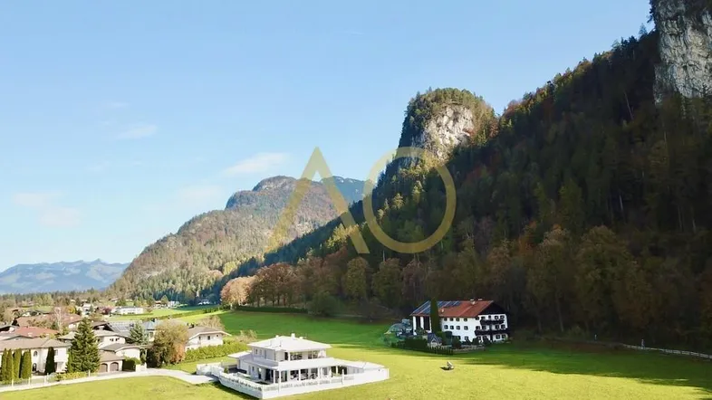 Luftaufnahme eines Anwesens mit weitläufigen Grünflächen und majestätischem Bergblick.