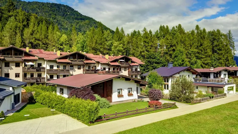 Traditionelle Gebäude in einer grünen Umgebung mit Bergen im Hintergrund.
