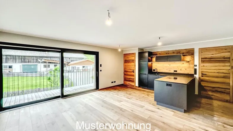 Helle Musterwohnung mit offener Küche, Holzboden und Zugang zu einem Balkon oder einer Terrasse.