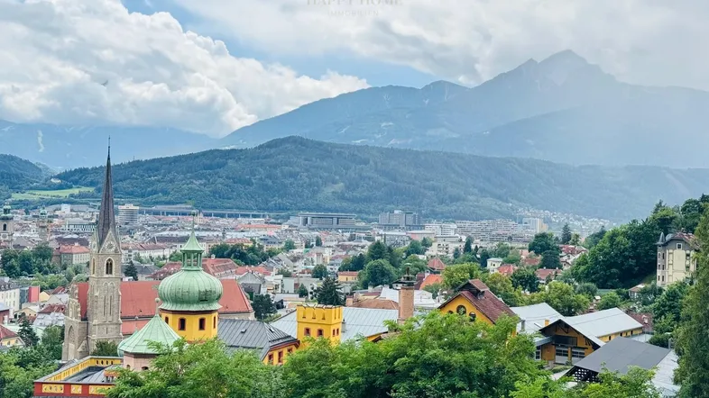 Panoramablick auf die Stadt Innsbruck mit historischen Gebäuden und majestätischen Bergen im Hintergrund.