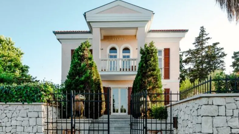 Elegante Villa mit klassischer Architektur, umgeben von Steinmauern und einem schmiedeeisernen Tor.