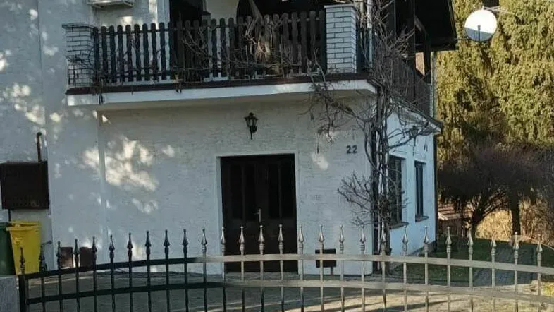 Ansicht eines Einfamilienhauses mit weißer Fassade, Balkon und einem gepflegten Vorgartenbereich.