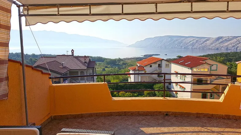 Geräumige Terrasse mit Markise, Fliesenboden und weitem Blick auf das Meer und die umliegende Landschaft.