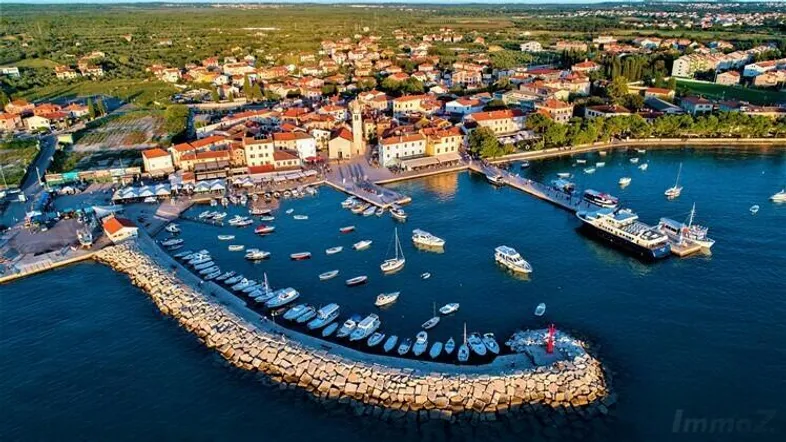 Luftaufnahme einer malerischen Küstenstadt mit belebtem Hafen, vielen Booten und traditionellen Gebäuden.