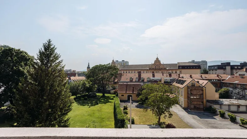 Weitblick über die Stadt mit grünen Flächen und historischen Gebäuden unter blauem Himmel.
