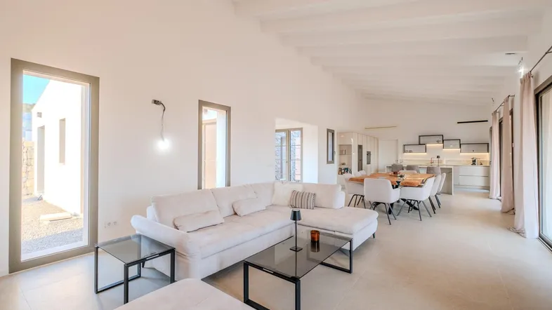 Helles, offenes Wohn- und Esszimmer mit bequemer Couch, modernem Esstisch und Zugang zum Außenbereich.