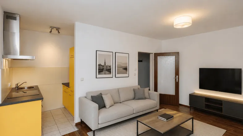 Helles Wohnzimmer mit offener Küche, Holzboden und moderner Einrichtung.