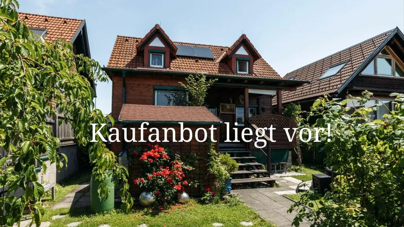 Charmantes Holzhaus mit rotem Dach und gepflegtem Vorgarten, umgeben von viel Grün.