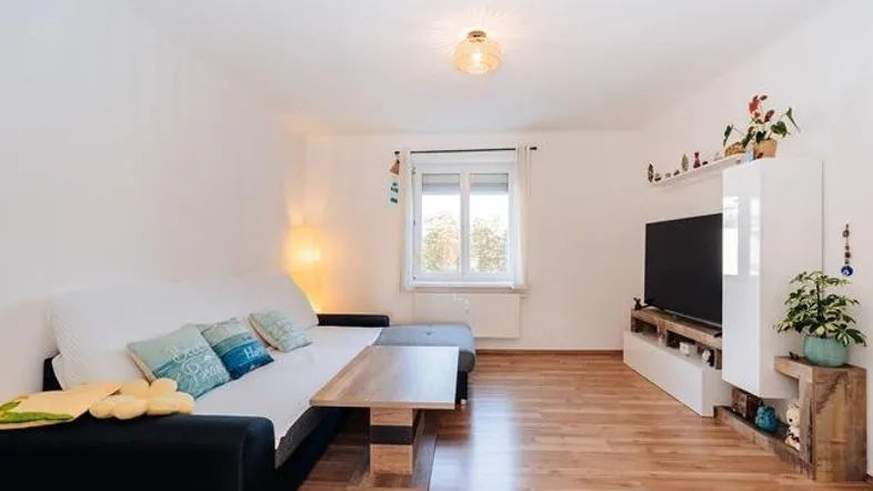 Helles Wohnzimmer mit Holzboden, bequemer Couch und TV-Möbeln, ideal zum Entspannen.