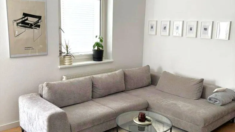 Helles Wohnzimmer mit modernem Ecksofa, Couchtisch und Parkettboden, ideal zum Entspannen.